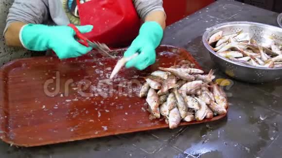 割市场中的鱼妇女手工清洗和切鲜鱼视频的预览图