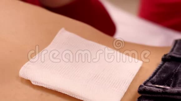 特写大师用贴片将棉巾固定在女孩腹部视频的预览图