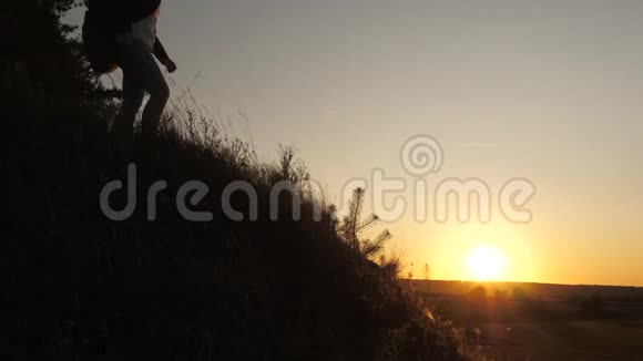 一位男性旅行者向攀登山顶的女性旅行者伸出手游客们在夕阳下爬山视频的预览图