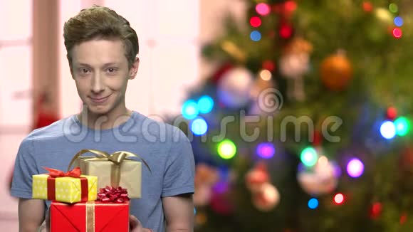 男孩在模糊的圣诞灯上送礼物盒视频的预览图