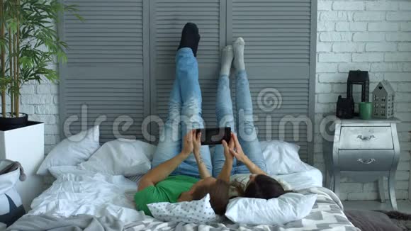 一对轻松的情侣在床上分享数码平板电脑视频的预览图