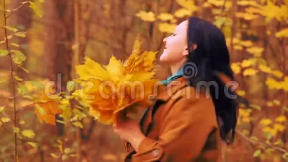 秋天公园里微笑的年轻女子手里拿着枫叶在旋转视频的预览图