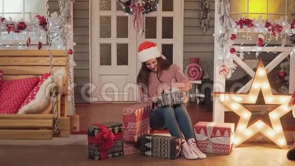 穿着圣诞帽和毛衣的女孩正坐在门廊里视频的预览图