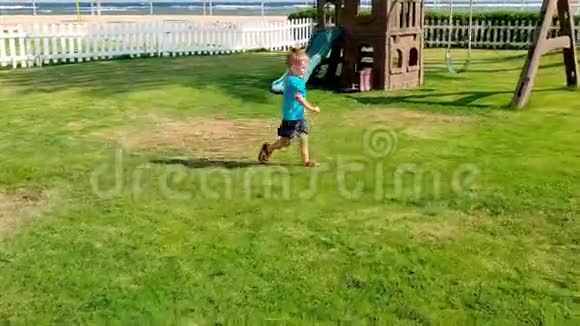 可爱的快乐男孩在操场草地上奔跑和玩球的4K镜头视频的预览图