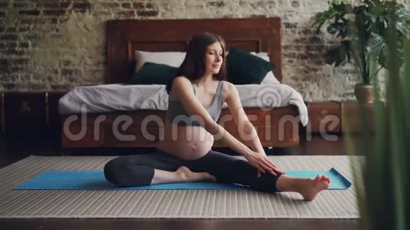 美丽的黑发女人期待妈妈做伸展运动弯着腰为妈妈练习瑜伽视频的预览图