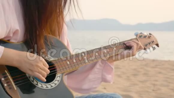 4K在日落时分她在沙滩上用轻柔的风弹着吉他感到放松视频的预览图