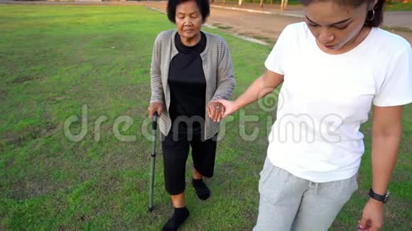 女子慢动作牵着老年妇女的手在公园散步视频的预览图