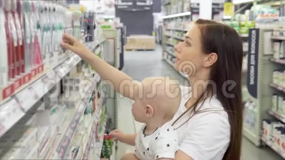 漂亮的女人带着小儿子在超市购物年轻的妈妈在市场上为家人选择牙膏视频的预览图
