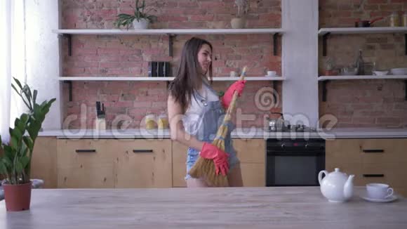 家务活快乐的家庭主妇在打扫房子的时候在扫帚上嬉戏跳舞视频的预览图