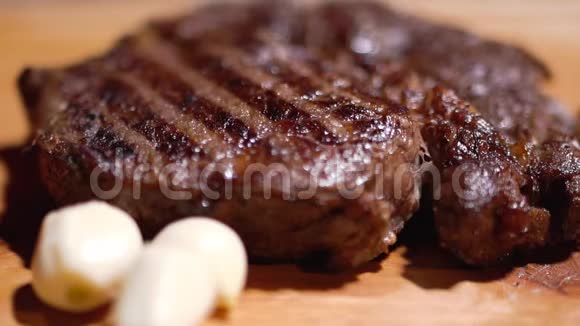 美味的烤牛排躺在切割板上大蒜紧贴新鲜的迷迭香落在肉上视频的预览图
