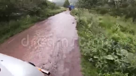 开车离开马路汽车用石头水坑和泥浆穿过马路在山路上旅行视频的预览图