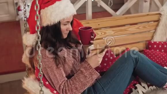 戴着圣诞帽的漂亮女孩在电话里发短信女人的圣诞祝福视频的预览图