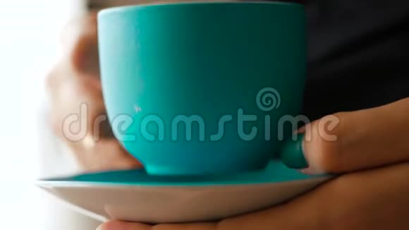美丽的女孩早上在厨房喝蓝色杯子里的咖啡特写视频的预览图