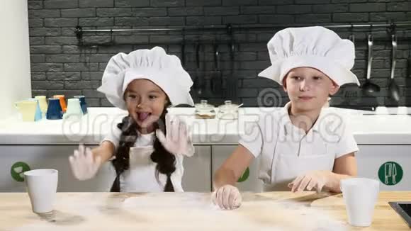 厨师小子两个戴厨师帽的孩子玩面团在家庭厨房玩得开心准备意大利面4k视频的预览图