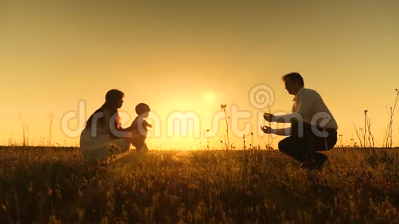 年轻的亚洲家庭在一个有一个婴儿在手的领域家庭幸福的概念美丽的阳光日落视频的预览图