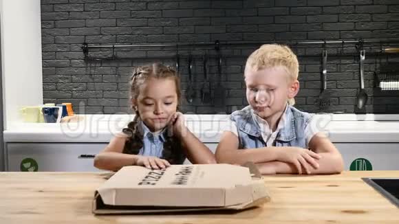 孩子们在吃饭两个漂亮的孩子打开披萨饼高兴地看披萨孩子们最喜欢的食物4k视频的预览图