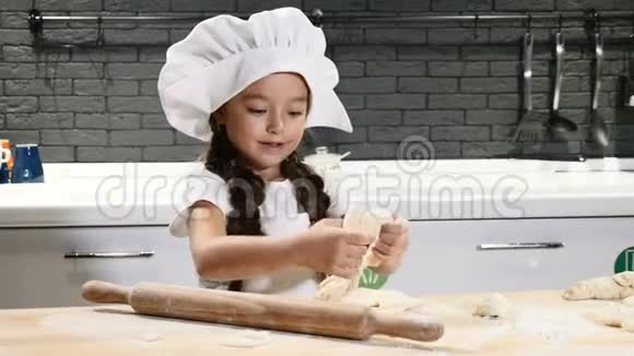 孩子们做饭戴厨师帽的小女孩玩面团和擀面杖在厨房里玩得开心4k视频的预览图