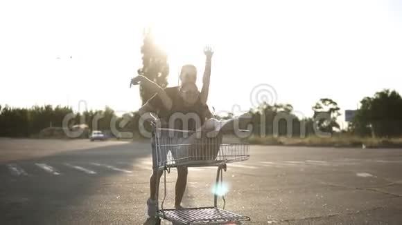 快乐的年轻夫妇在停车场的户外骑马男人推着购物车里面有个女孩她在洗衣服视频的预览图