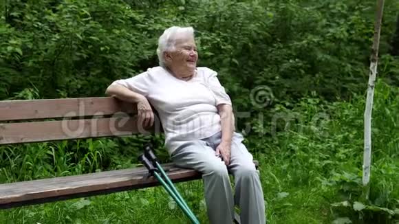 老奶奶坐在公园的长凳上休息视频的预览图