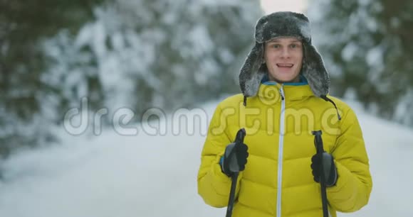 在冬天的森林旅行中带着滑雪板的微笑男人和他的妻子在看一些奇怪的东西视频的预览图