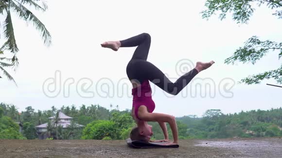 女孩练习倒立瑜伽姿势的自然背景视频的预览图