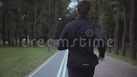 在公园里工作的人慢动作后景健身运动员在森林小巷慢跑相机倾斜向下拍摄视频的预览图