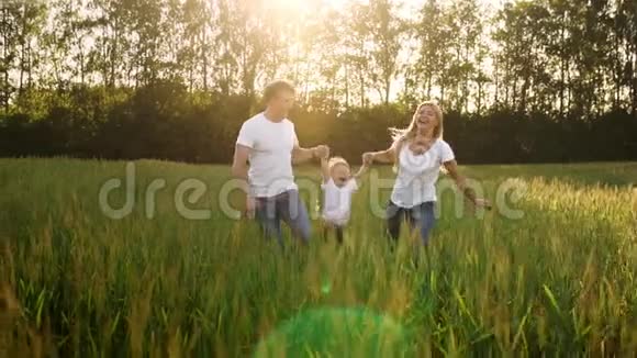 爸爸妈妈和儿子走在田野里穿着白色T恤和牛仔裤的尖钉手上挥舞着它视频的预览图