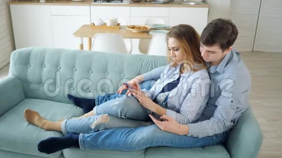 男人和女孩坐在沙发上用智能手机上网视频的预览图