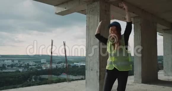 在工地的顶部一位年轻的女工带着安全帽背对着镜头跳舞视频的预览图