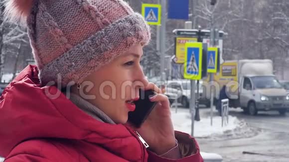 一位年轻女子在雪地冬城散步时打电话的肖像慢动作视频的预览图