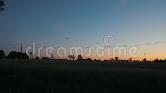 日落时的地平线与风力涡轮机电力和农场房屋的剪影视频的预览图