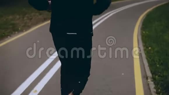 穿黑色运动服的4K人在一个绿色公园里跑步后景运动员在安静的城市小巷里锻炼生活方式拍摄视频的预览图