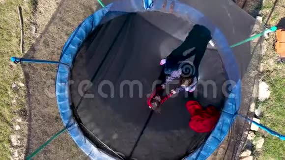 母亲带着女儿在蹦床上玩得开心用无人驾驶飞机跳跃的鸟瞰图视频的预览图