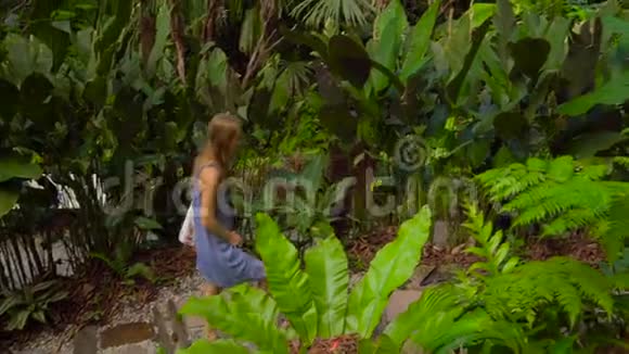 Steadycam拍摄了一位年轻妇女和她的儿子她正在参观一个热带花园里面有异国情调的果树和植物视频的预览图