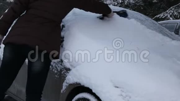 一个冬天的早晨一个女人在雪地上打扫汽车视频的预览图