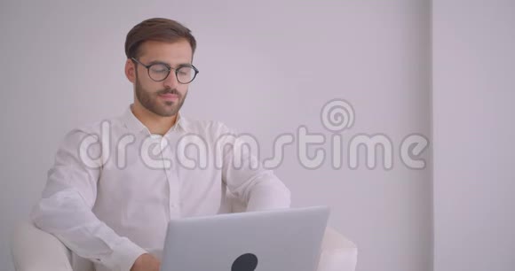 成人英俊成功的高加索商人戴着眼镜用手提电脑看镜头的特写肖像视频的预览图