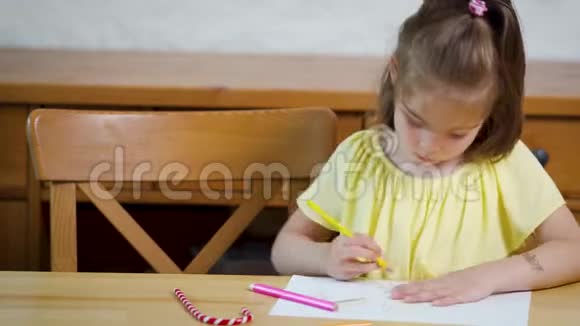 小女孩穿着黄色的连衣裙用蜡笔在纸上画画视频的预览图