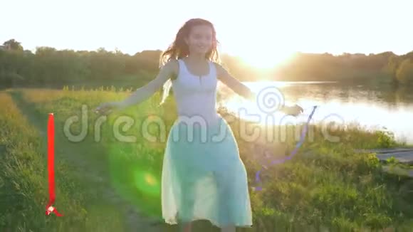 笑着笑着积极向上的少女手里拿着丝带走在湖边的绿色自然上视频的预览图