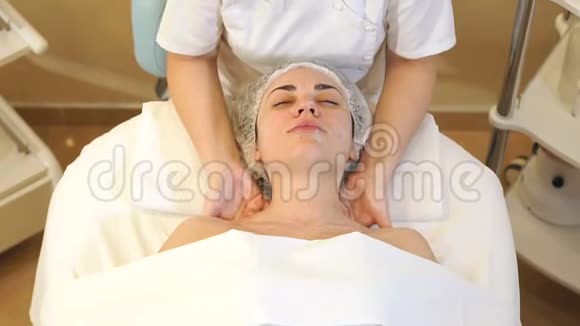 一个按摩师在水疗沙龙里用奶油做面部按摩的女孩视频的预览图