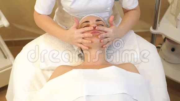 一个按摩师在水疗沙龙里用奶油做面部按摩的女孩视频的预览图