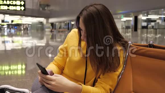 在机场候机室使用智能手机的年轻女子视频的预览图