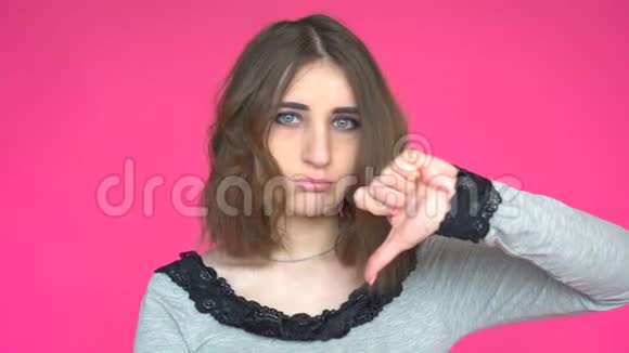 年轻女子伸出大拇指在粉红色的背景下拍照视频的预览图