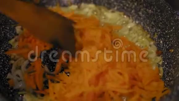 特写镜头用一个木制的香料烹饪胡萝卜和白葱在煎锅中用姜黄烤油视频的预览图