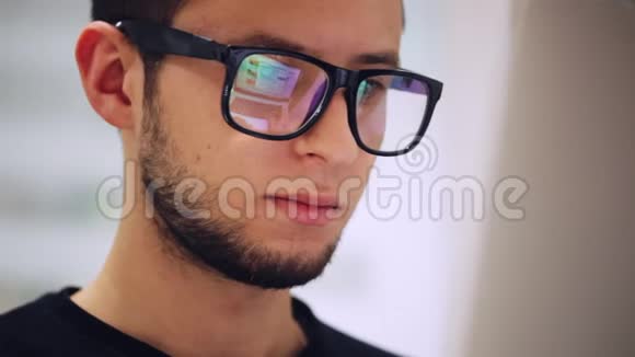 一个在电脑上工作的人的特写镜头反射一个带眼镜的屏幕视频的预览图