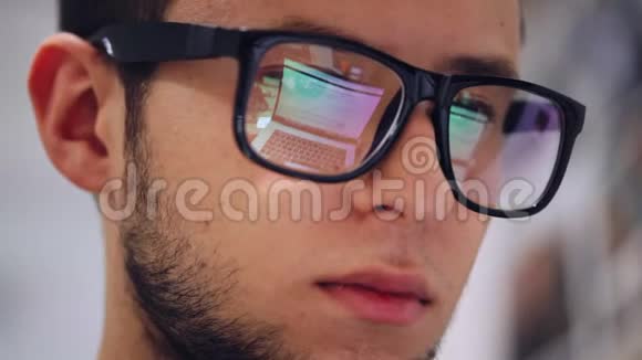 一个在笔记本电脑上工作的人的特写镜头用眼镜反射屏幕视频的预览图