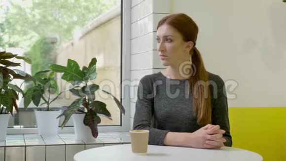 年轻漂亮的女人梳着马尾辫坐在咖啡馆里直视着镜头交叉着双手严肃而关心视频的预览图