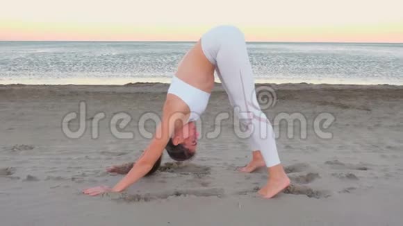 年轻女子在日出时在沙滩上做瑜伽视频的预览图