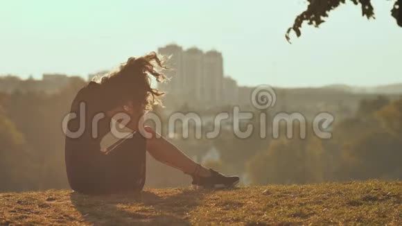 悲伤的女孩剪影独自坐在草地上如此孤独和哭泣视频的预览图