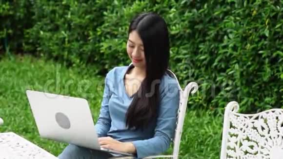 肖像美丽的亚洲年轻女子坐在公园里在家里用笔记本电脑休闲放松视频的预览图