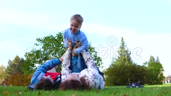 幸福的家庭躺在草坪上母亲和父亲抱着儿子抱在怀里抱着他的头孩子笑了关于视频的预览图